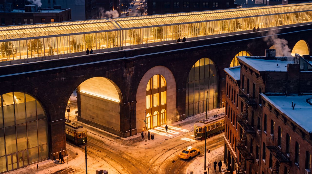 After dark: The same street at night: the mile of glass along the viaduct glowing warm gold over the city, the arches lit from within, snow under the streetlights.