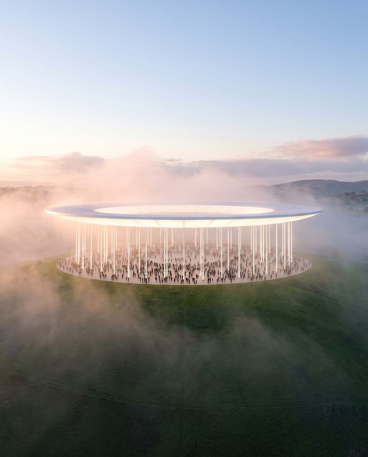 A luminous ring roof on slender columns over a round plaza full of people, on a green hill in morning mist.